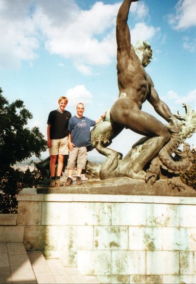 Zwei Personen vor einer großen Bronzestatue auf einem Steinsockel.