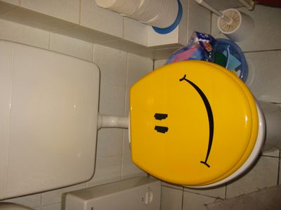 Gelber Toilettendeckel mit aufgemaltem Gesicht.