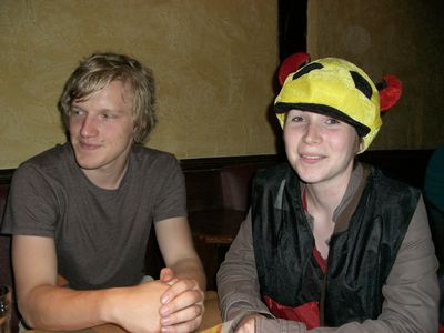 Zwei junge Leute an einem Kneipentisch, eine Person trägt eine bunte Fußball-Mütze.