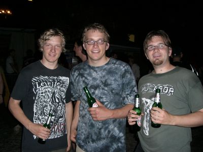 Drei junge Männer mit Bierflaschen bei Nacht.