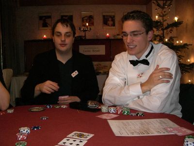 Zwei Männer an einem Pokertisch, einer mit Fliege und weißem Hemd.